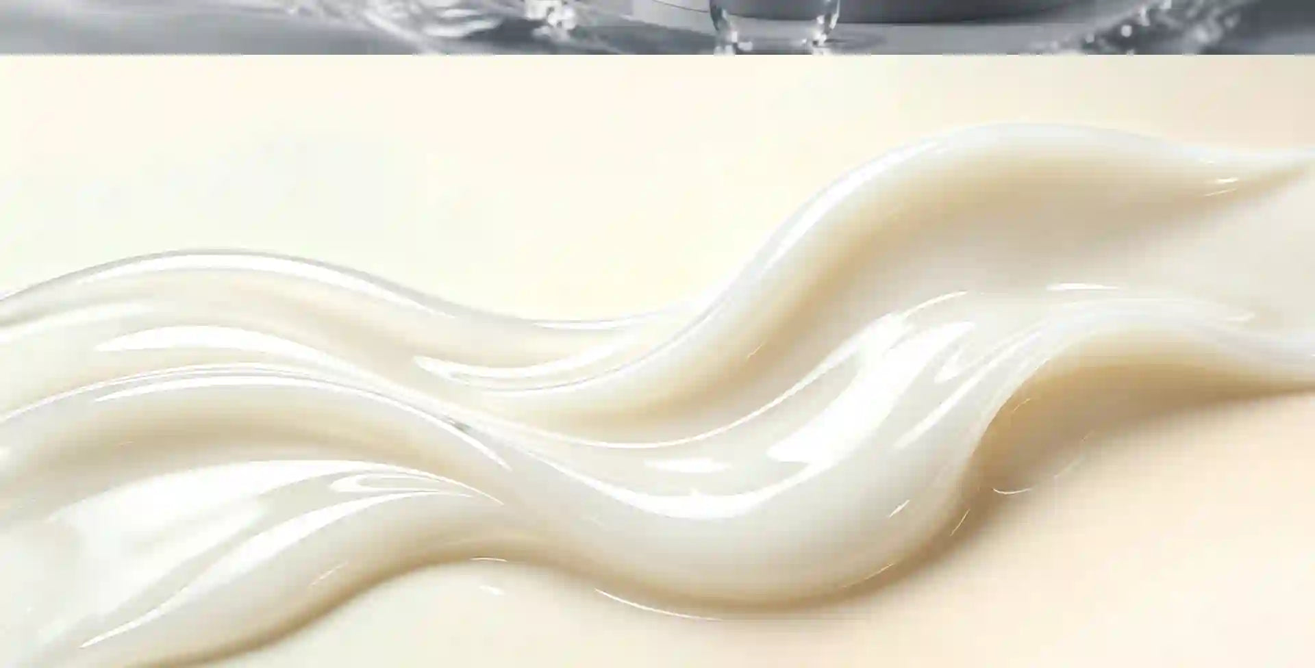 A close-up of a glossy, creamy off-white liquid or gel swirled in smooth waves on a pale beige surface.