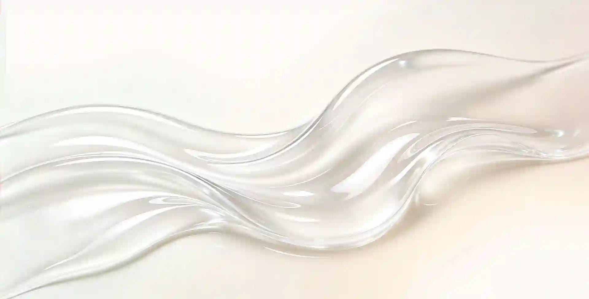 A close-up of a glossy, transparent liquid or gel swatch with soft wavy contours on a light cream background.