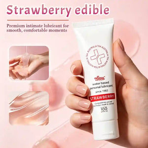 Tube of strawberry-flavored personal swallowable lubricant held by a hand with a pink background