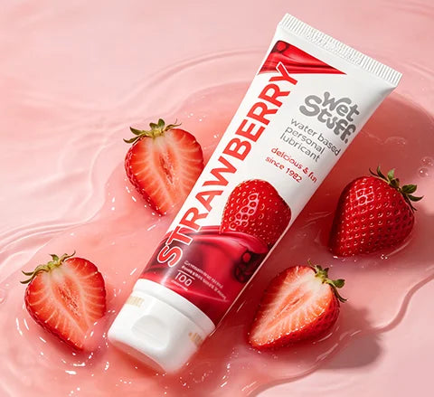 Tube of strawberry-flavored libido like whoopee gel personal lubricant surrounded by strawberries on a pink libido insemination gel 