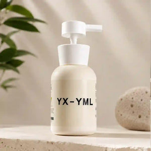 A cream-colored pump lube bottle with a white pump dispenser, featuring the text 'YX-YML' on the front, set on a stone surface with a blurred plant and decorative stone in the background.