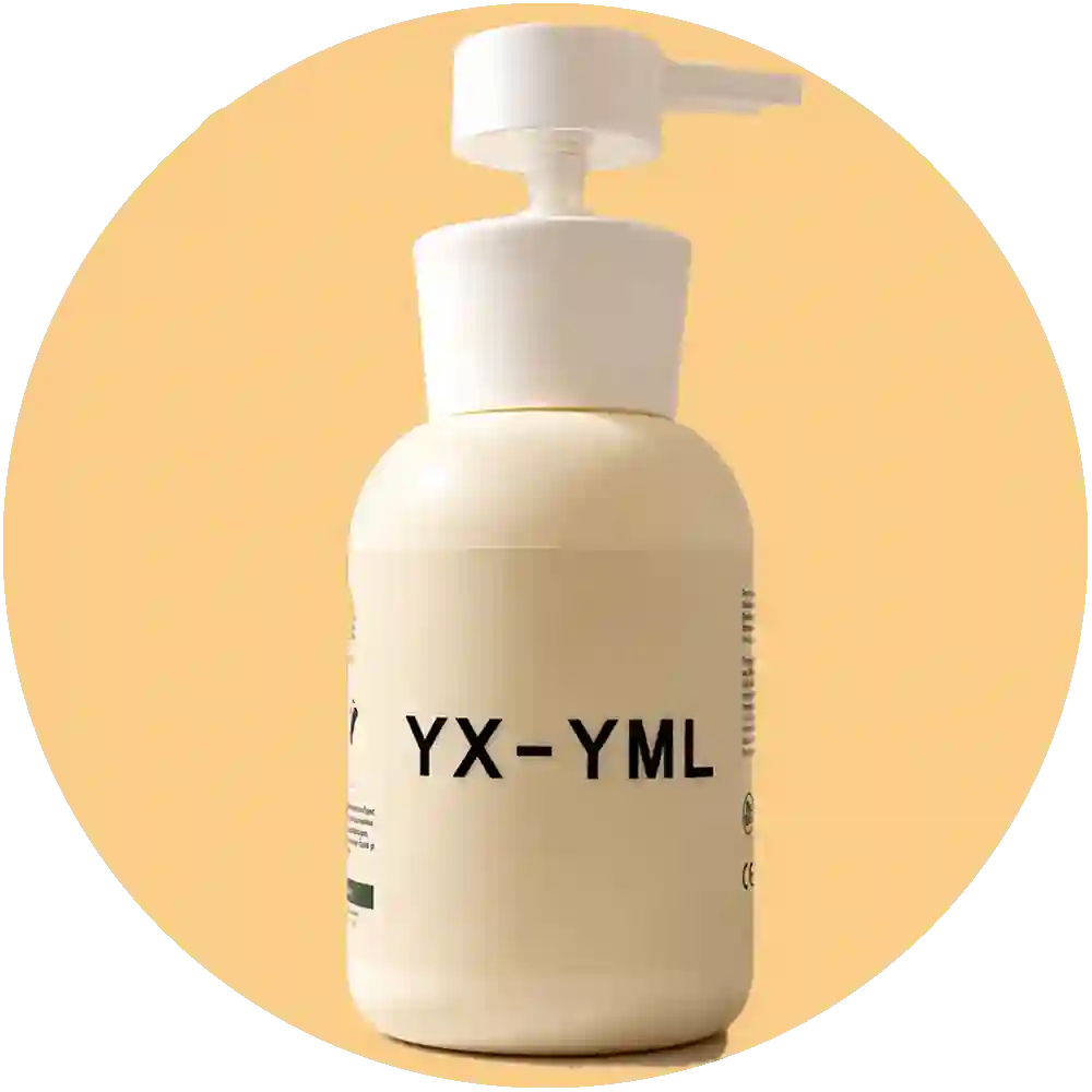 A cream-colored pump lube bottle with black text reading 'YX-YML' on the front, set on a light surface with soft shadows. A green leaf and a textured stone slab are visible in the background.