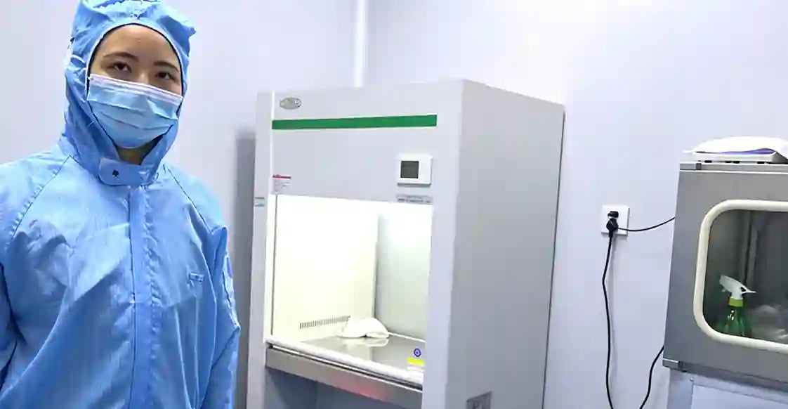 Person in a blue protective suit standing next to a laboratory cabinet arouselube manufacturer 