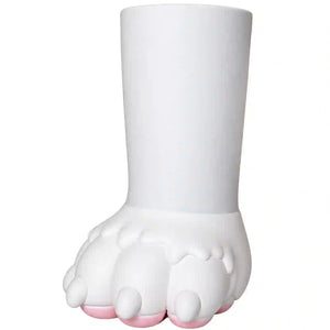 A white sculptural plant pot shaped like a stylized paw with a cylindrical stem, featuring small pink accents on the toes, set against a plain white background.