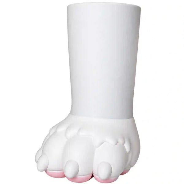 A white sculptural plant pot shaped like a stylized paw with a cylindrical stem, featuring small pink accents on the toes, set against a plain white background.