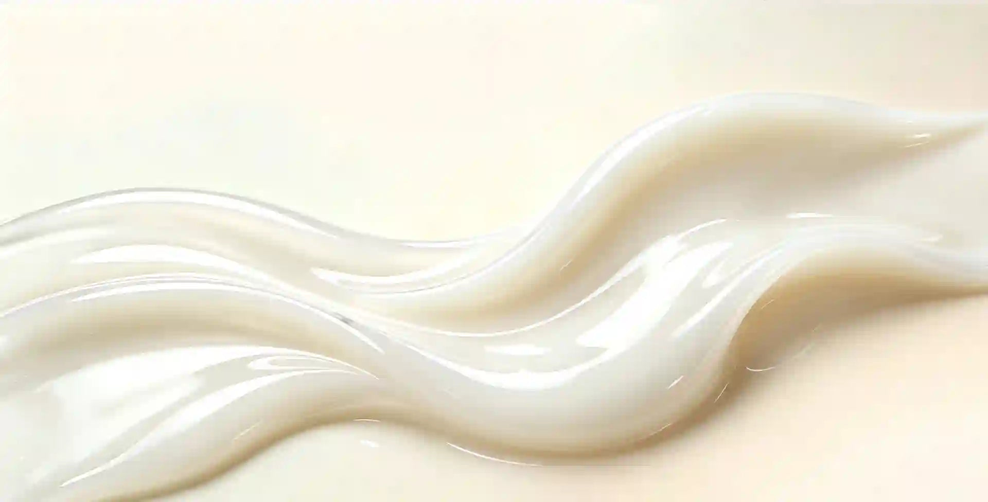 A close-up of smooth, creamy white personal lube liquid with soft wavy contours on a pale cream background.